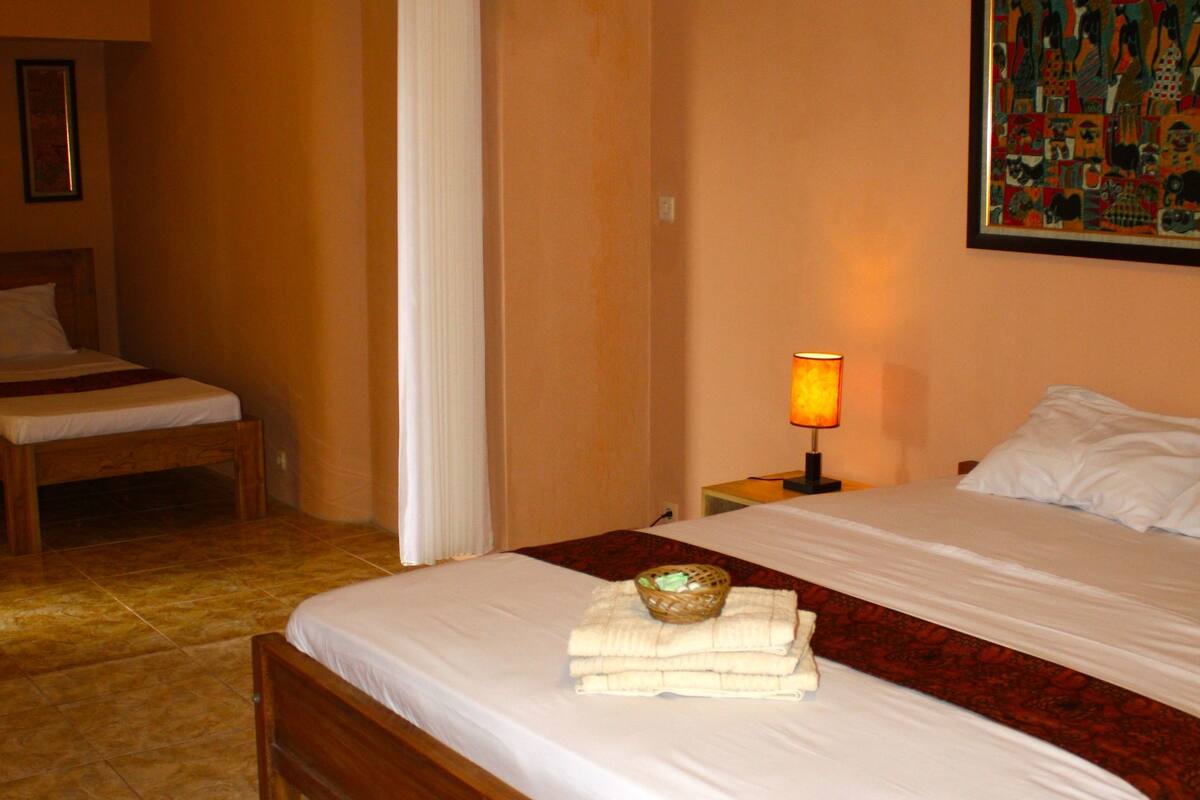 A hotel room with a large bed, a bedside table with a lamp, a chair, and a painting on the wall.