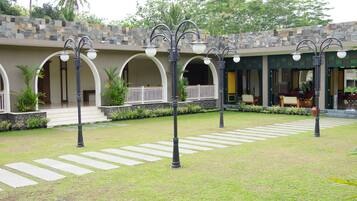 A courtyard with a stone wall, arched walkways, and outdoor seating areas.