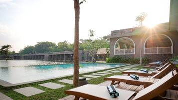 A poolside area with lounge chairs and a building with arched windows in the background.