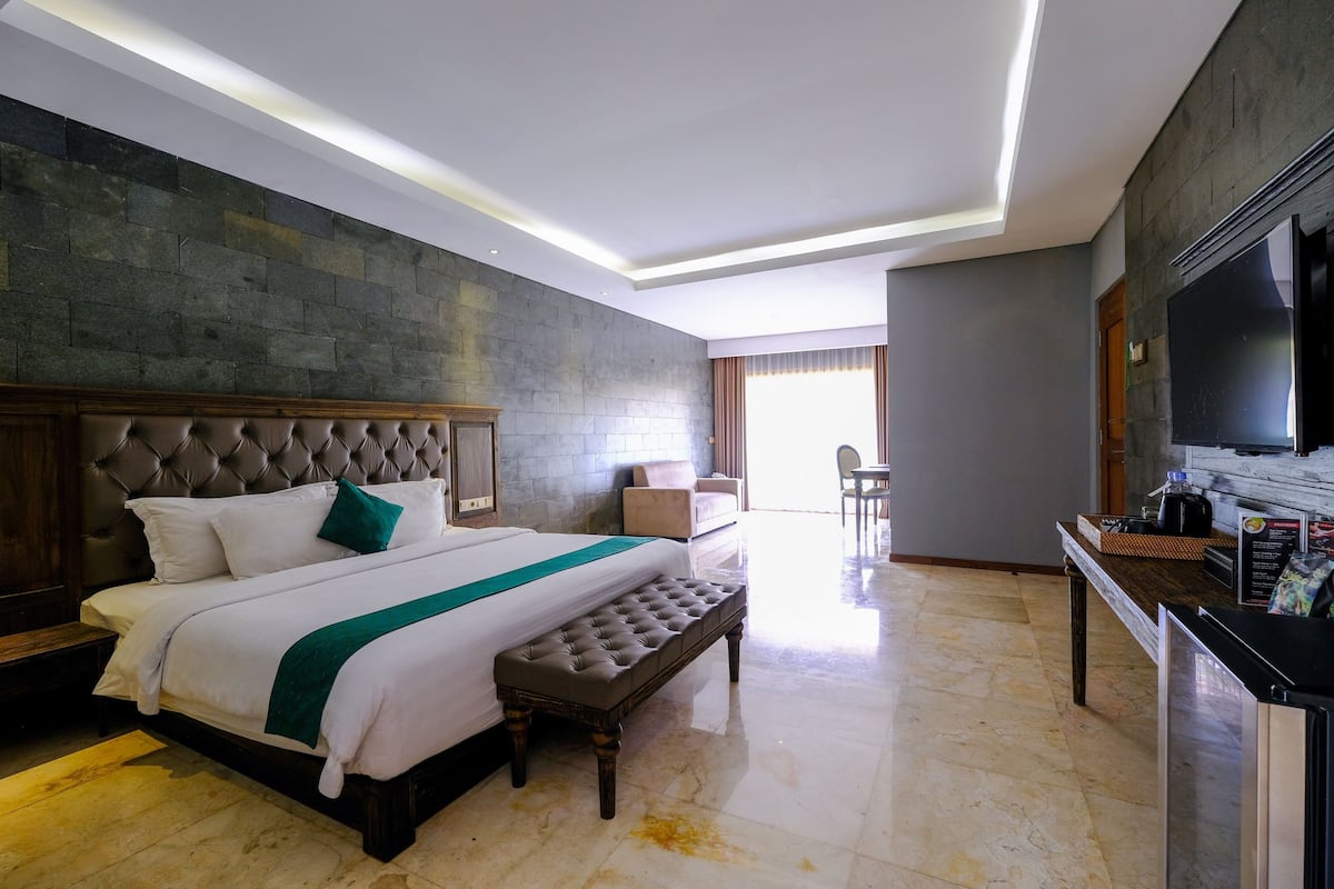 Une chambre d’hôtel avec un grand lit, un banc, une télévision et un coin repas.