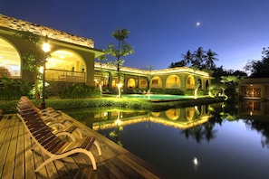A tranquil hotel courtyard at dusk with a reflective pool, wooden deck, and illuminated architecture. - The Westlake Hotel & Resort Yogyakarta (Sleman)