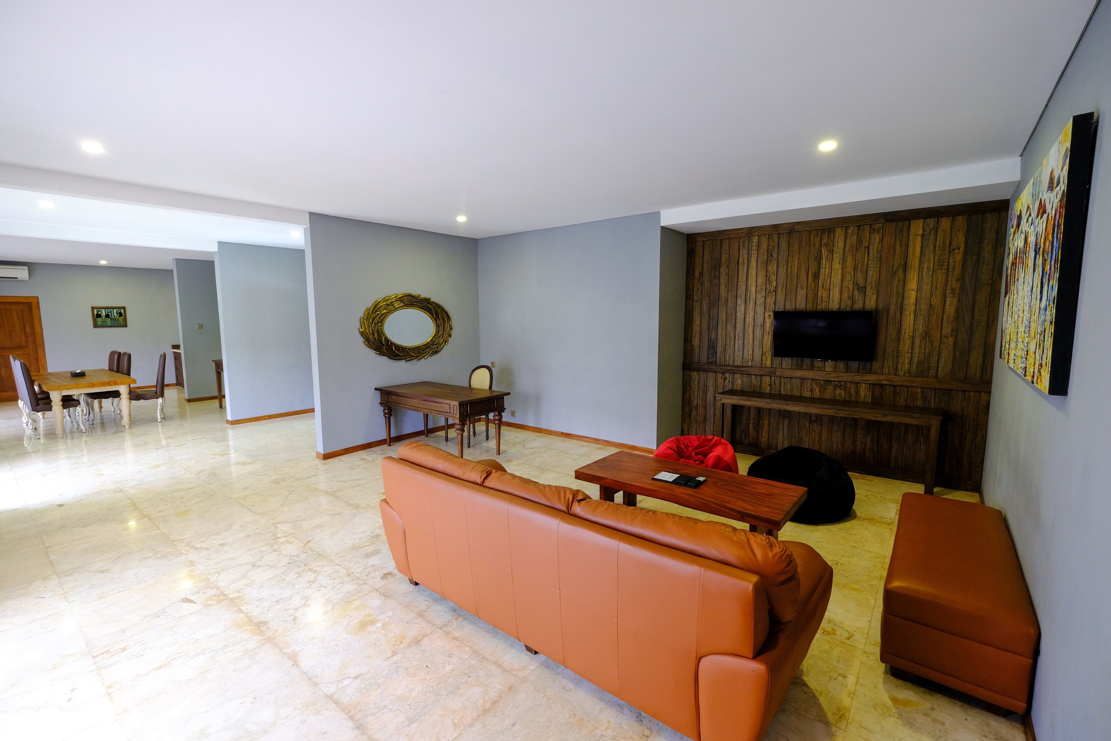 A modern living room with a sofa, a wooden table, and a TV mounted on the wall.
