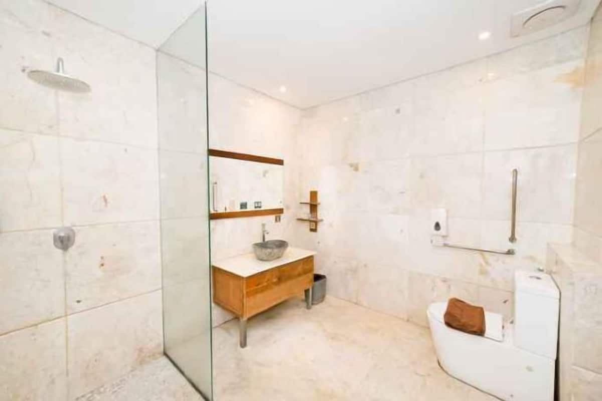 Une salle de bain moderne avec une douche à parois de verre, un meuble-lavabo en bois avec un vasque et des toilettes blanches.