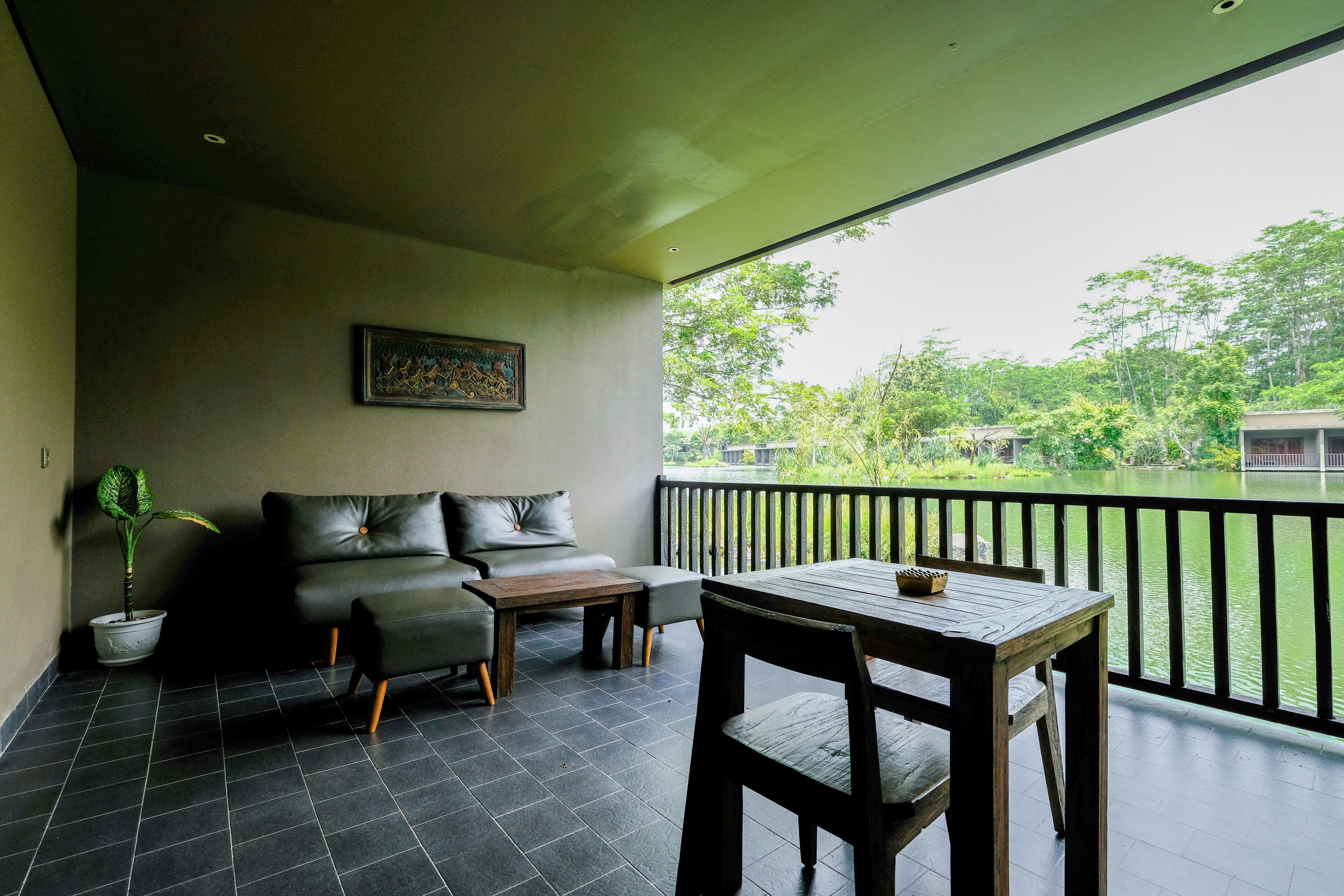 Ein Balkon mit einer Couch, Tisch und Stühlen, der auf ein Gewässer und Grünflächen blickt.