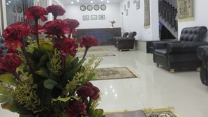 Una sala de estar moderna con un sofá de cuero negro, una mesa de centro y un gran arreglo floral.