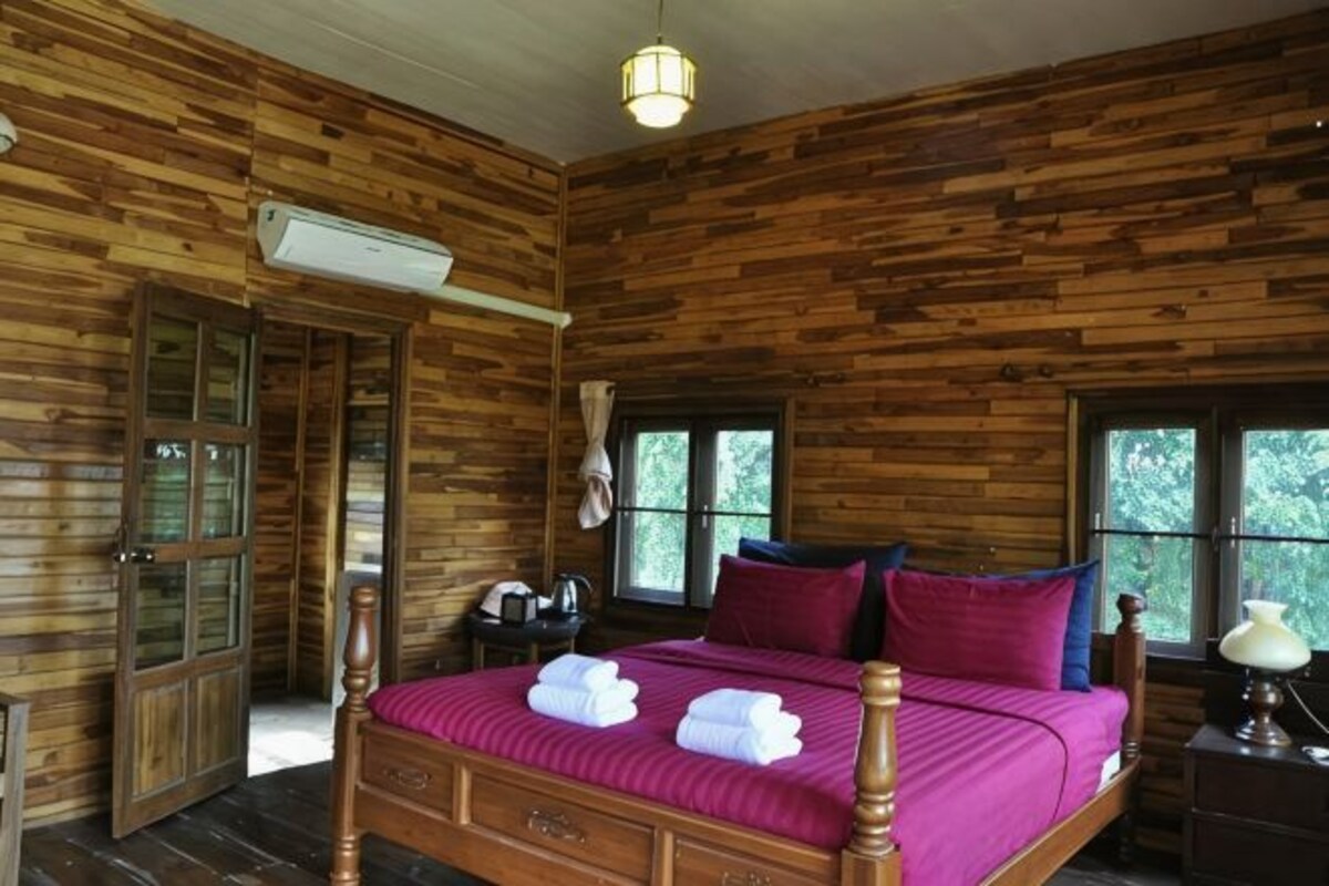 Una habitación con paneles de madera, una cama, un escritorio y un ventanal.