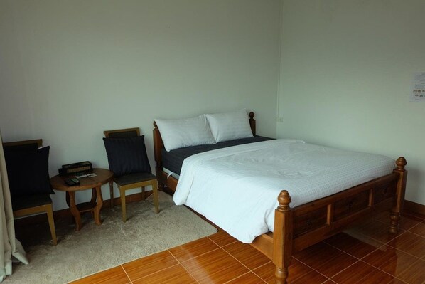 A bedroom with a wooden bed, a small round table, a chair, and a sofa. - Mai Ngern Mai Thong Resort (Muak Lek)