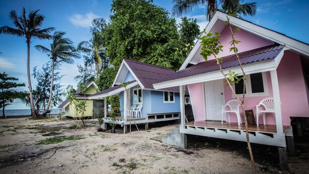 A row of beach cottages with a sandy beach and palm trees in the background. - The Pier Koh Phangan (Ko Pha-ngan)