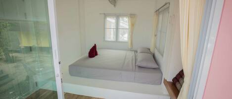 A room with a bed, a window, and a fan.