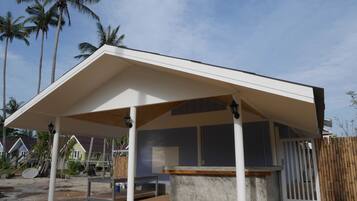 A covered outdoor area with a concrete floor, a wooden bench, and a table.