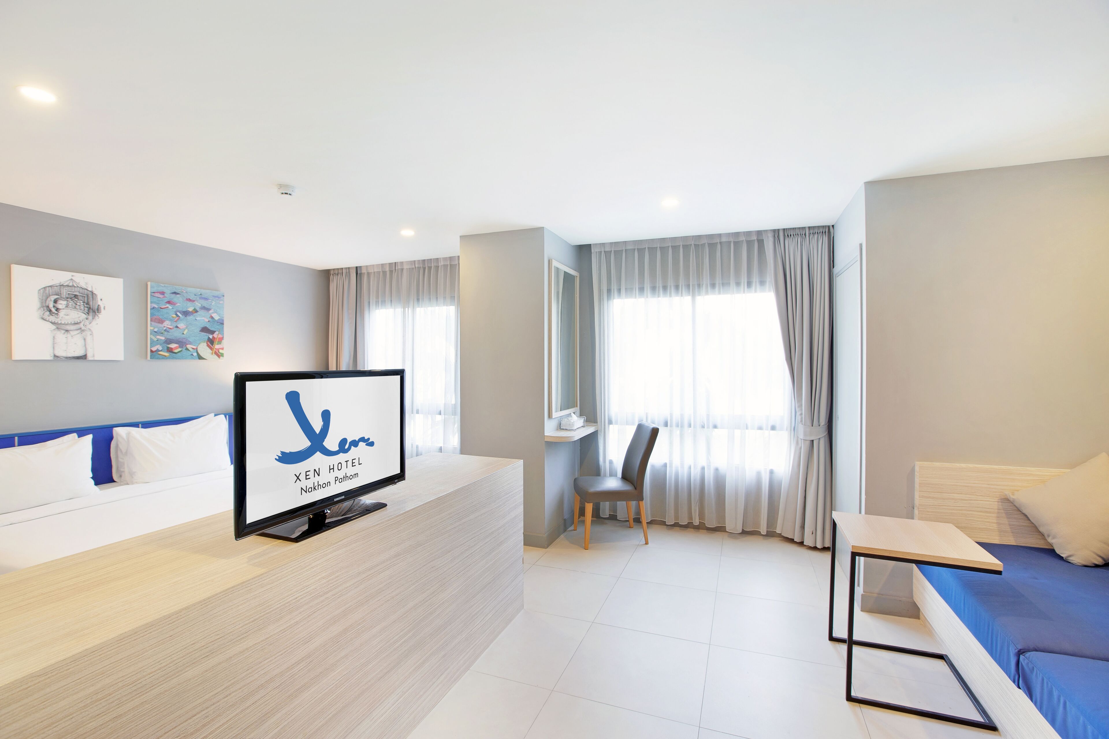 A hotel room with a bed, a desk, a chair, and a TV on the desk.
