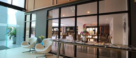 A modern interior with a reception desk, white chairs, and a glass partition.
