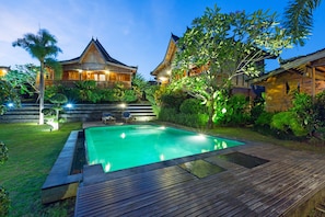 A traditional wooden villa with a swimming pool, surrounded by lush greenery and well-lit pathways. - Dawas Villa (Tibubeneng)