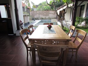 A wooden dining table with chairs, a small potted plant, and a tiled floor. - Dawas Villa (Tibubeneng)