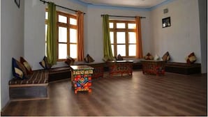 A room with a wooden floor, two windows with curtains, a sofa, and a small table.