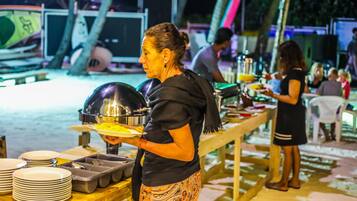Guests enjoy a sumptuous spread at the outdoor buffet, featuring a variety of dishes and utensils.