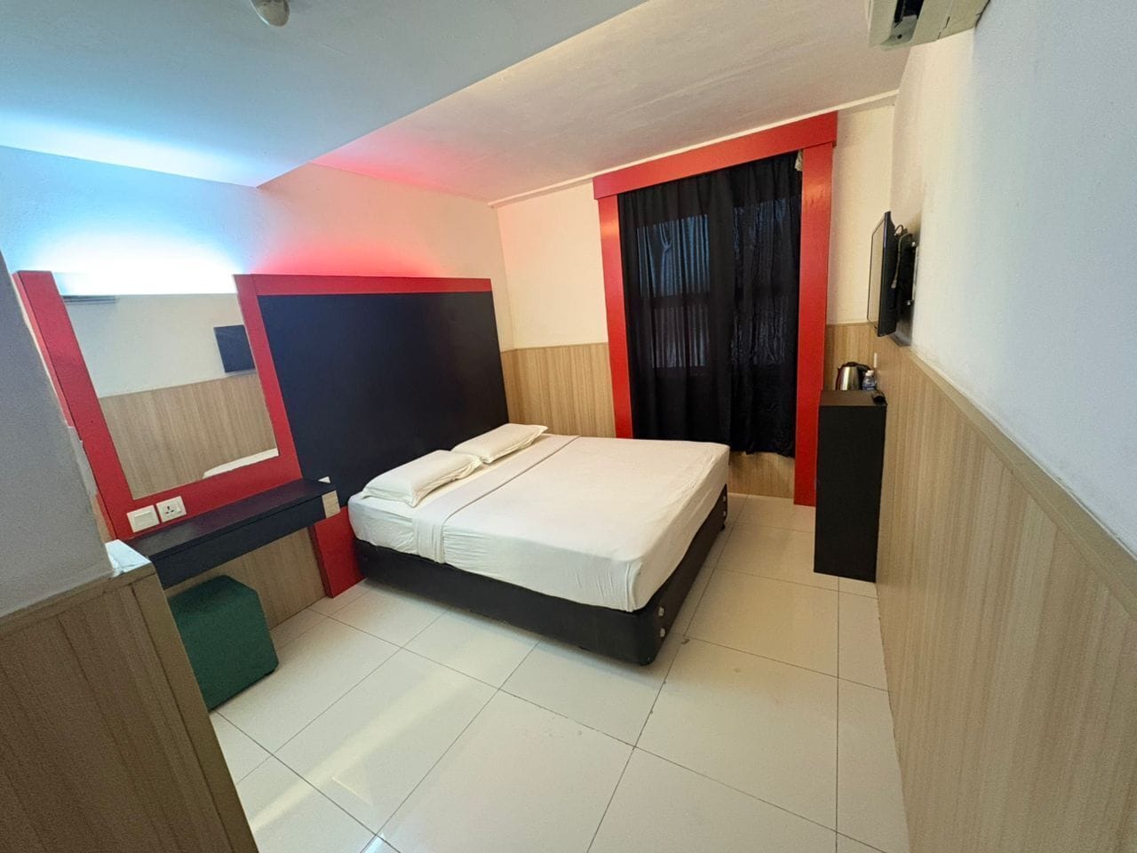 A modern hotel room with a bed, a desk, and a wardrobe.