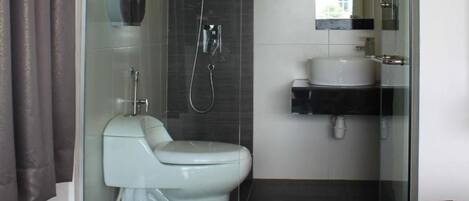 Un baño moderno con ducha envuelta en vidrio, inodoro blanco y lavamanos con encimera negra.