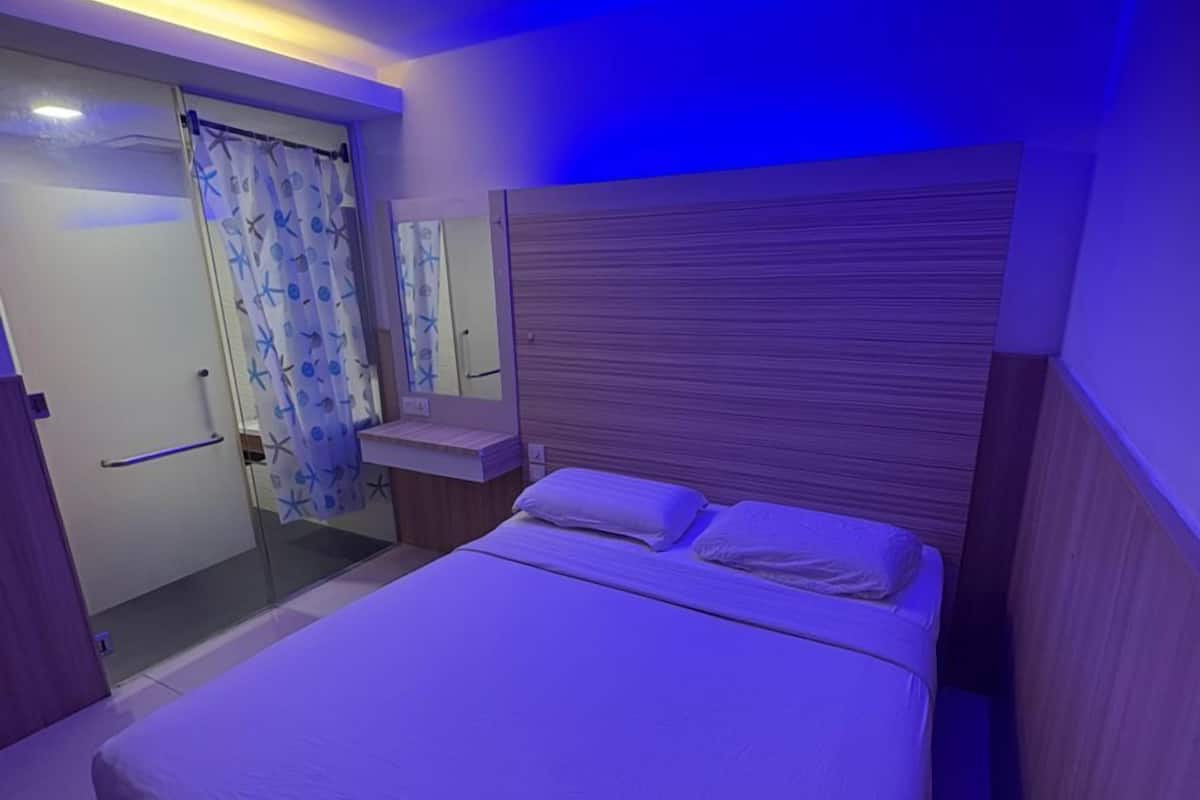 Ein Schlafzimmer mit einem Bett, einem Nachttisch, einem Spiegel und einer Tür mit Vorhang.