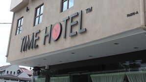 Un hotel con fachada moderna, ventanas amplias y un llamativo letrero que dice "TIME HOTEL".