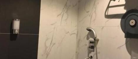 A bathroom with a toilet, a towel rack, and a shower with a handheld showerhead.
