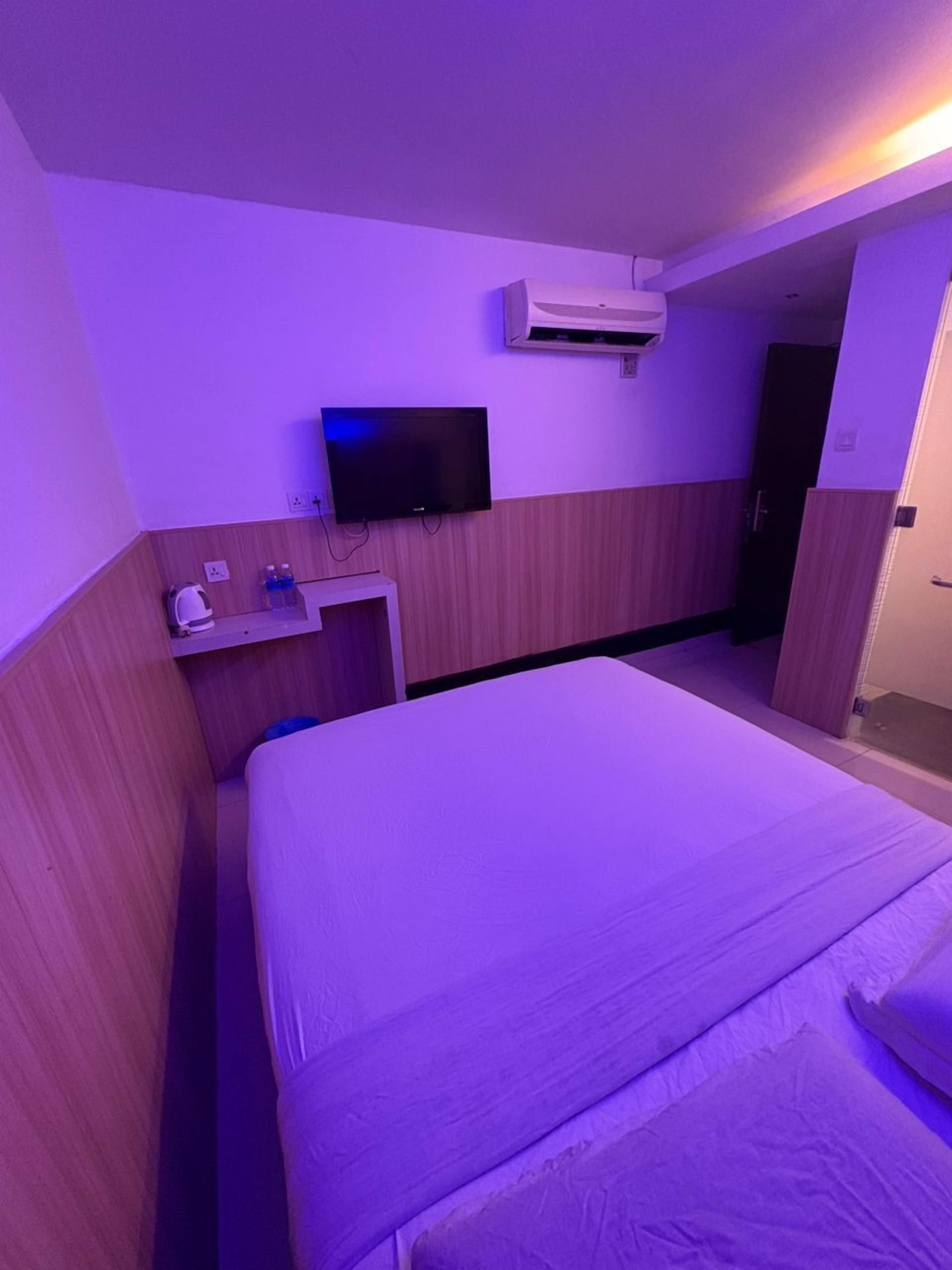 Habitación de hotel con cama, televisión, aire acondicionado y una pequeña mesa con artículos de aseo.