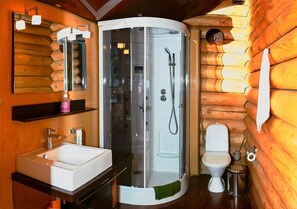 Bathroom features a corner shower, sink, and toilet, with wooden accents and a shelf for toiletries.