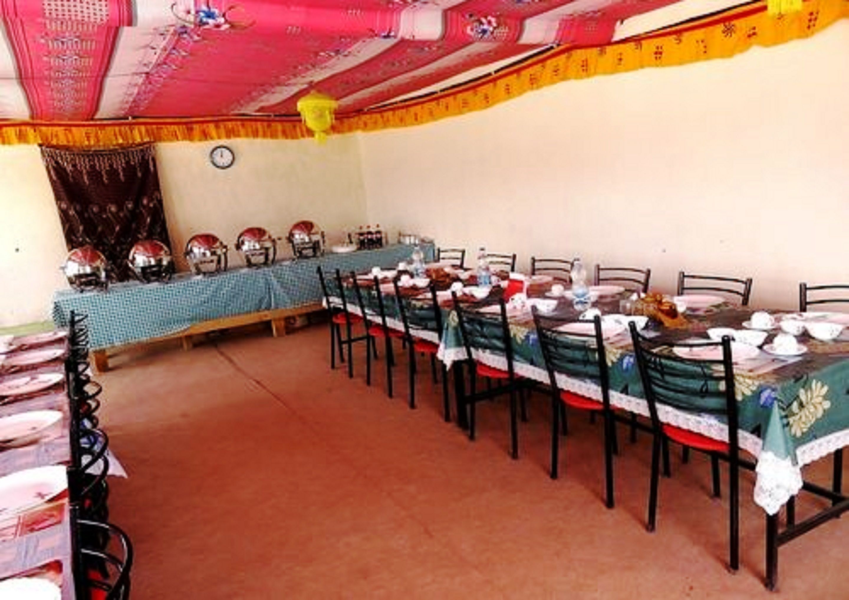 A dining area with a long table set for multiple people, chairs, and a clock on the wall.