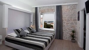 Un dormitorio moderno con una cama grande, una pared de acento de piedra, una ventana con vistas y una planta en maceta.