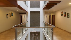 Un interior amplio con una escalera central, barandas de cristal y obras de arte en las paredes.