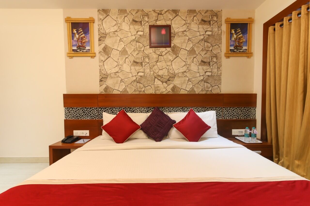 A hotel room with a large bed, a stone wall, and two framed pictures.