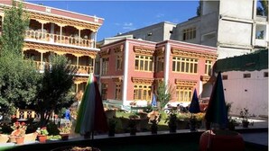 A courtyard with a pool, potted plants, and a building with a balcony.