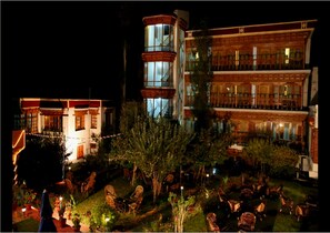 A multi-story building with a courtyard. The building has multiple balconies and large windows. There are outdoor seating areas with chairs and tables.