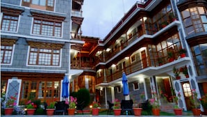A multi-story hotel with balconies, outdoor seating, and potted plants.