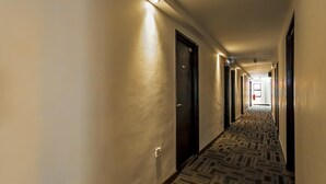 A hotel hallway with patterned carpet, doors on both sides, and a light source on the left. - Time Hotel Sunway (Petaling Jaya)