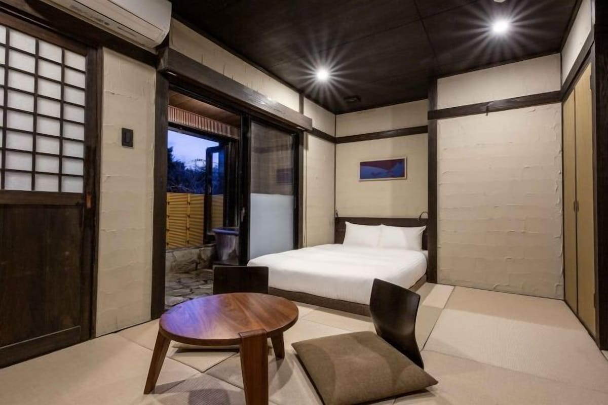 Una habitación con una cama, una mesa de madera y una silla.