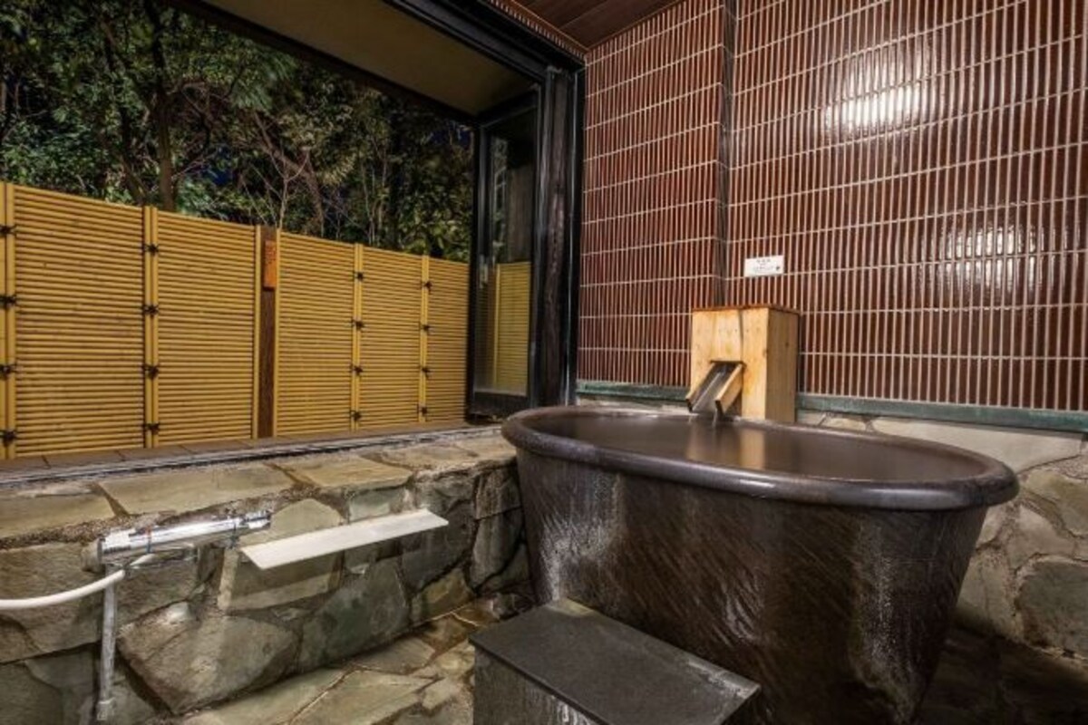 Un bagno con un lavabo in pietra, una divisoria in legno e una parete rivestita di piastrelle.