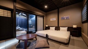 A modern hotel room with a large bed, a round dining table, and sliding doors leading to a balcony. - Ryokan Nagomitsuki (Beppu)