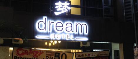A hotel named 'dream' with a neon sign, a parked car, and a 'Promotion RM 50' sign.