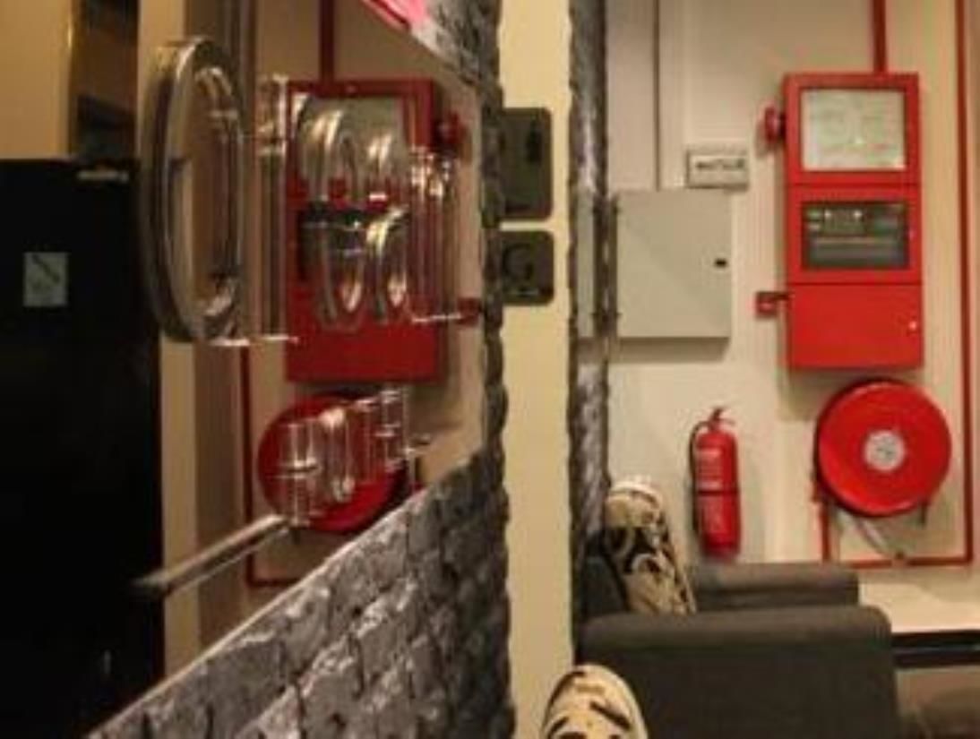 Una cocina con electrodomésticos de acero inoxidable, un extintor rojo y un detector de incendios en la pared.
