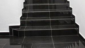 A staircase with black steps leading to a landing. - Dream Hotel (Klang)