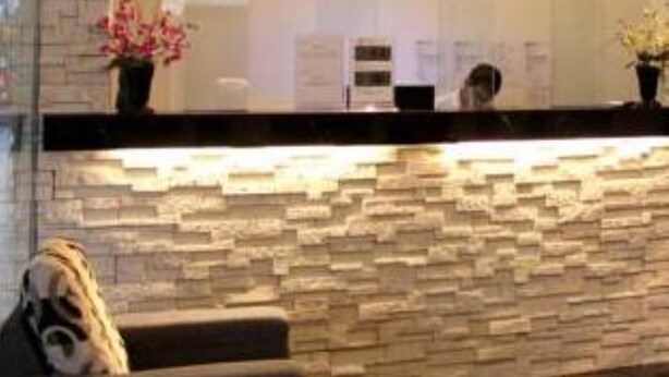 A reception area with a stone wall and a counter. - Dream Hotel (Klang)