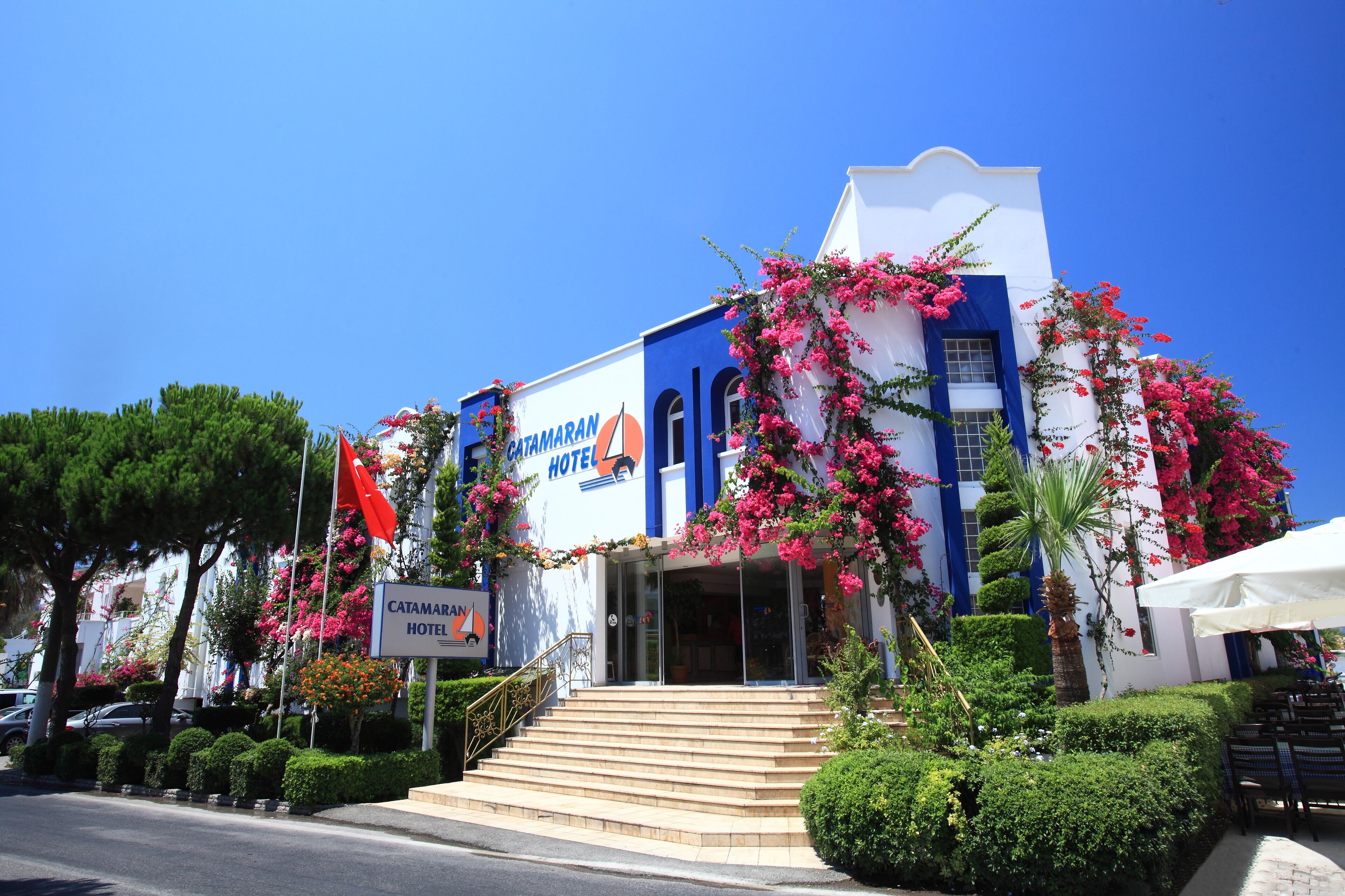 A hotel with a blue and white facade, a staircase leading to the entrance, and a sign indicating it is a hotel.