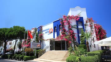 A hotel with a blue and white facade, a staircase leading to the entrance, and a sign indicating it is a hotel.
