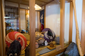 Une pièce de style japonais traditionnel, avec un sol recouvert de tatamis, un paravent en papier de riz (shoji) et une collection de poupées kokeshi.
