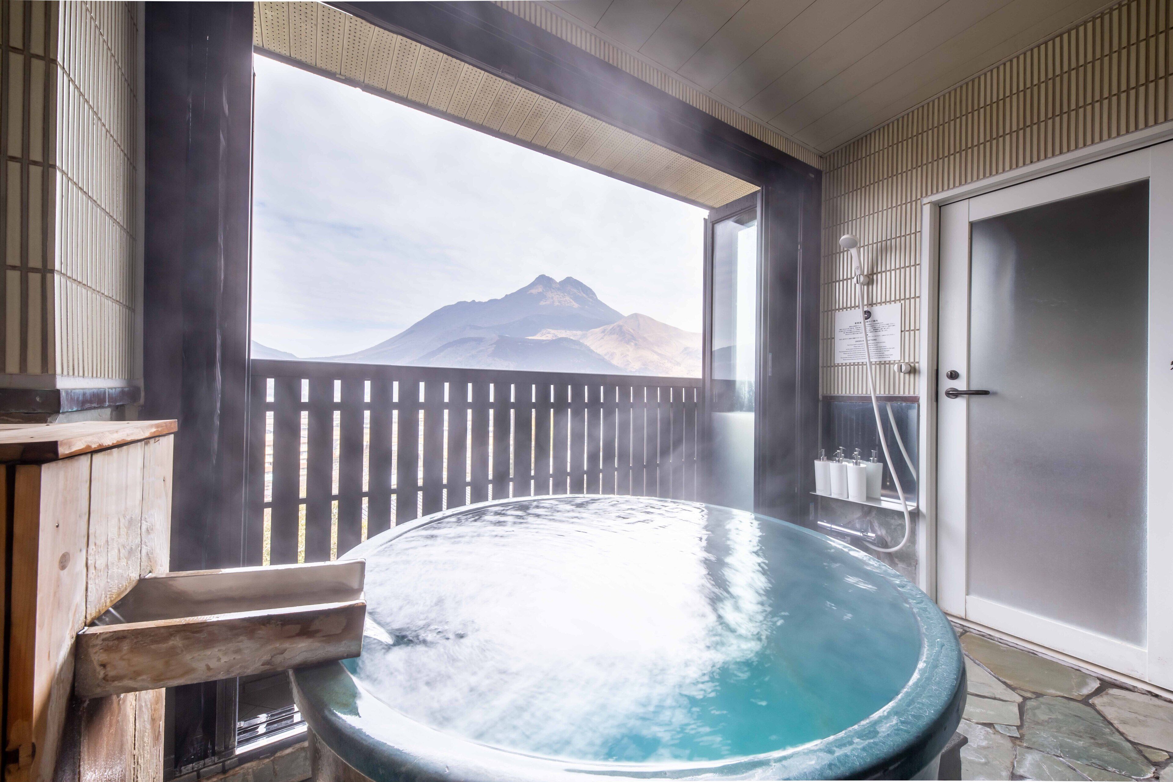 Un jacuzzi con vista a la montaña, terraza de madera y una puerta con perchero.
