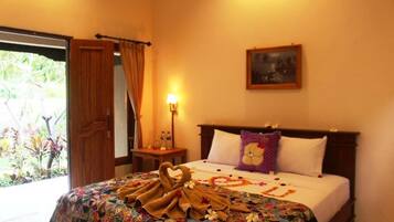 Habitación de hotel con cama, mesita de noche, lámpara, puerta y ventana.
