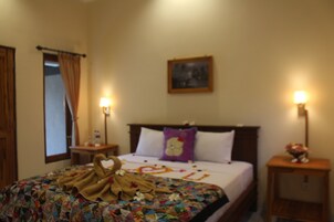 Habitación de hotel con cama, dos mesitas de noche, un ventanal con cortinas y un cuadro colgado en la pared.