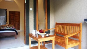 Une pièce avec un lit en bois, une chaise en bois, une petite table avec une assiette, un pichet et un bol.