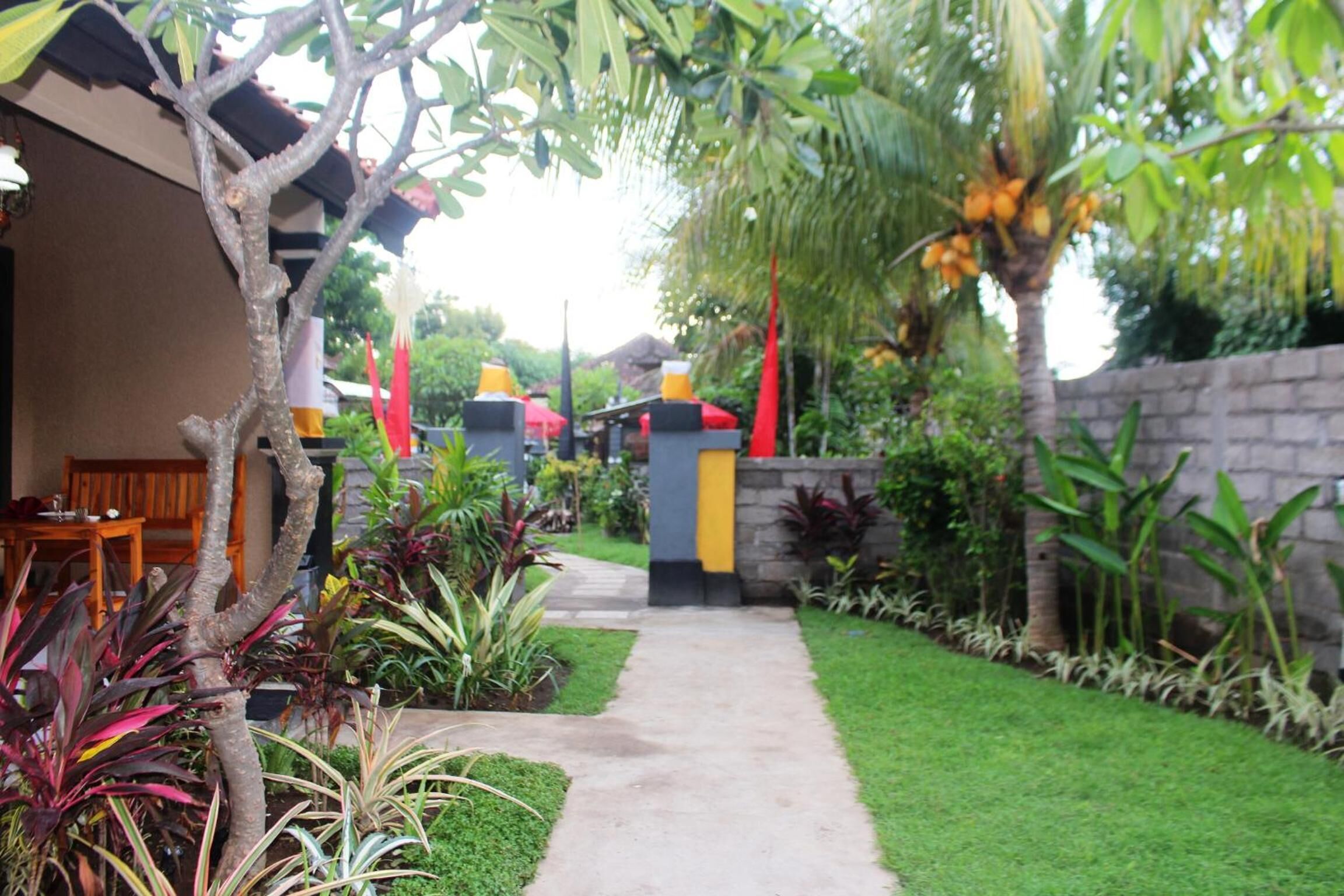 A pathway leading to a building with a stone wall and various plants.